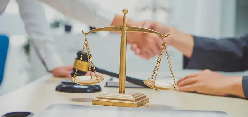 Attorney and client shaking hands behind a scale