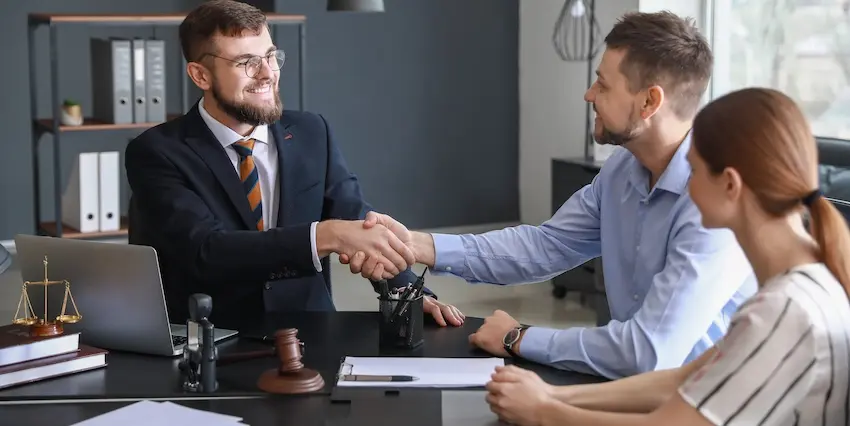 Liability disputes resolution meeting with an attorney is shaking hands with two accident victims in a law office at Hodgins & Kiber. LLC.