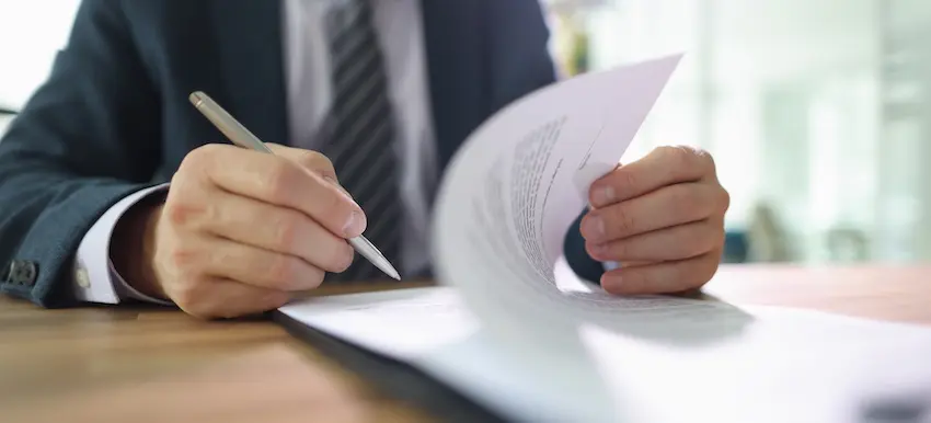 A partially at fault driver is reviewing legal documents and a settlement agreement with an attorney during a consultation.