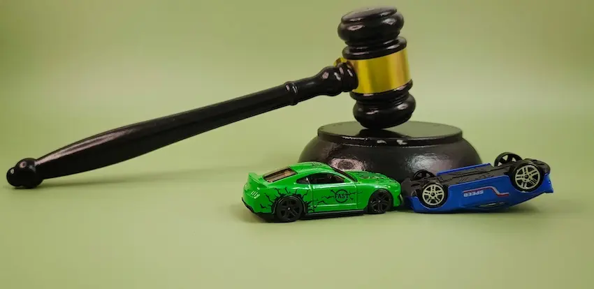 A legal gavel with a green and blue toy car which represents a car accident claim litigation and the insurance settlement process at Hidgins & Kiber LLC in Atlanta.