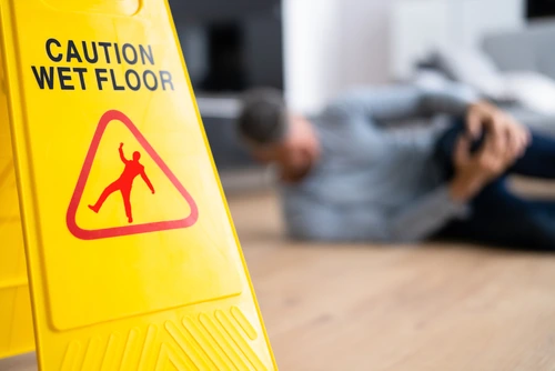 A man falls near a wet floor sign and needs a slip and fall accident lawyer.