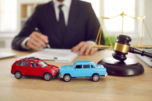 A Georgia car accident attorney works at a desk with two model cars.