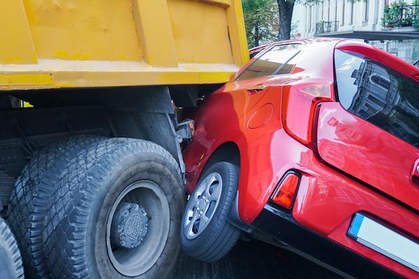 Truck accident scene with a car hit by a truck